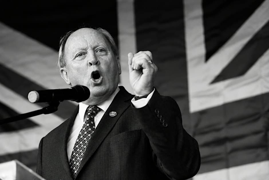 Jim Allister KC MP speaking at a podium in front of a Union flag